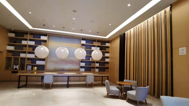 Un vestíbulo moderno con una zona de estar central, una amplia estantería y un panel decorativo en la pared.