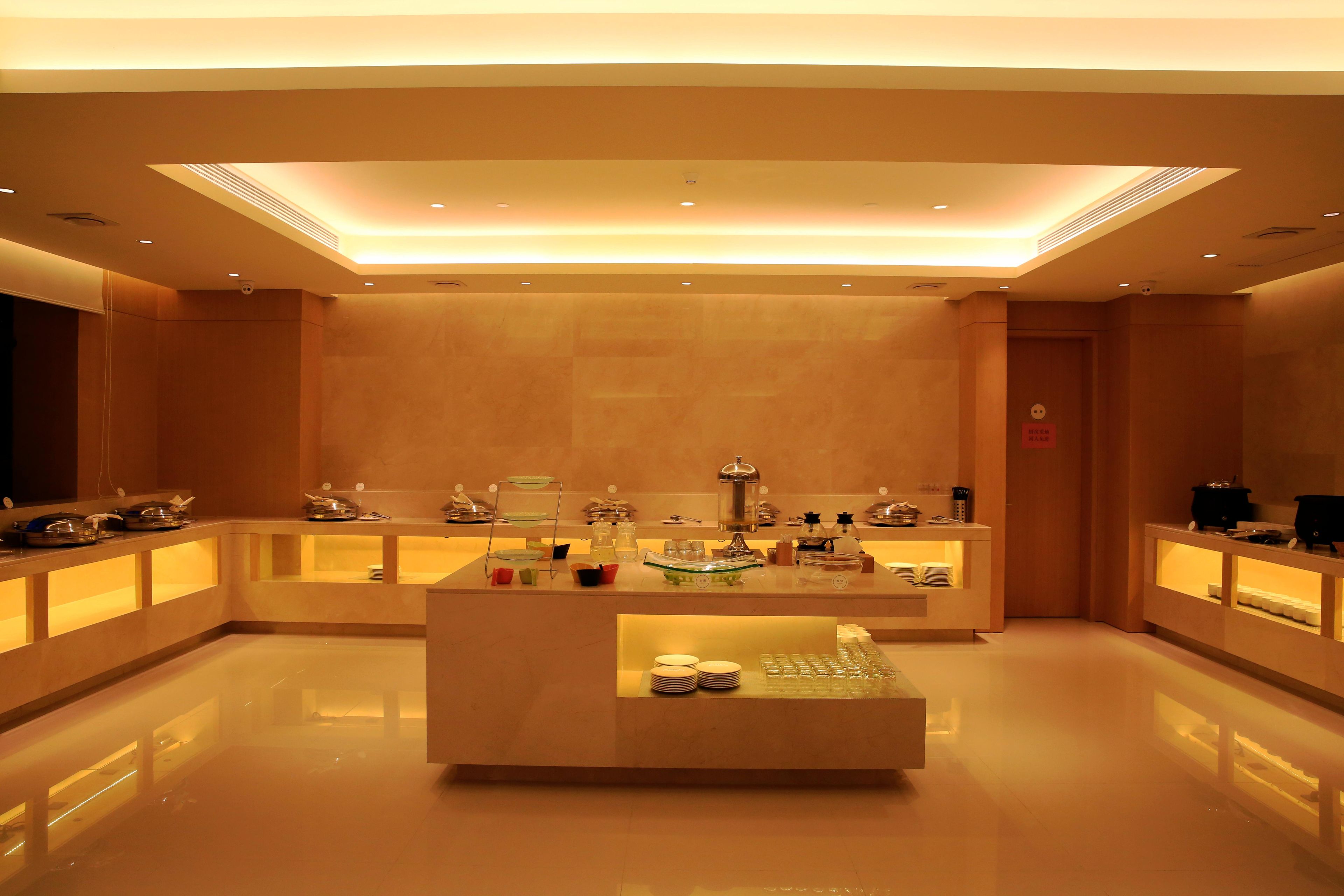 A modern hotel lobby with a central reception desk, glass display cases, and a polished floor.