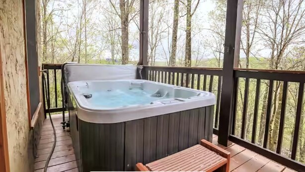 A hot tub on a wooden deck with a view of trees.