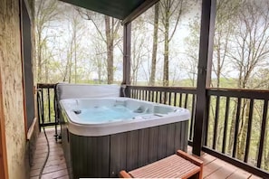 Un bain à remous sur une terrasse en bois, avec vue sur les arbres.