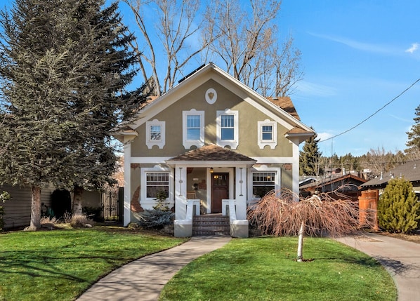 A two-story house with a front porch, a driveway, and a well-maintained lawn.