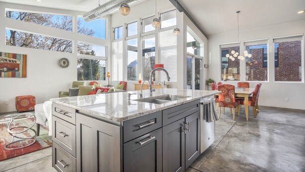 A modern kitchen with a large island, stainless steel appliances, and a dining area with red patterned chairs. - Modern Luxury I Mountain Views- central location- 4BR/3Ba (Colorado Springs)