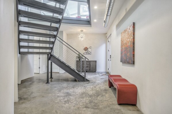 A modern interior with a staircase, a chandelier, and artwork on the walls.