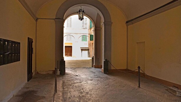 A corridor with an arched ceiling, a hanging light fixture, and a chain barrier. - Stilmoderno 2 rooms apartment in Siena (Siena)
