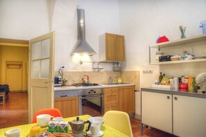 Uma cozinha compacta com armários de madeira, um fogão e uma área de jantar com mesa posta para dois.
