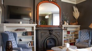 A living room with a fireplace, a television, and a bookshelf. - Pert House (Potsdam)