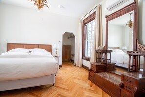 A bedroom with a wooden bed, a dresser, a mirror, and a window with curtains.