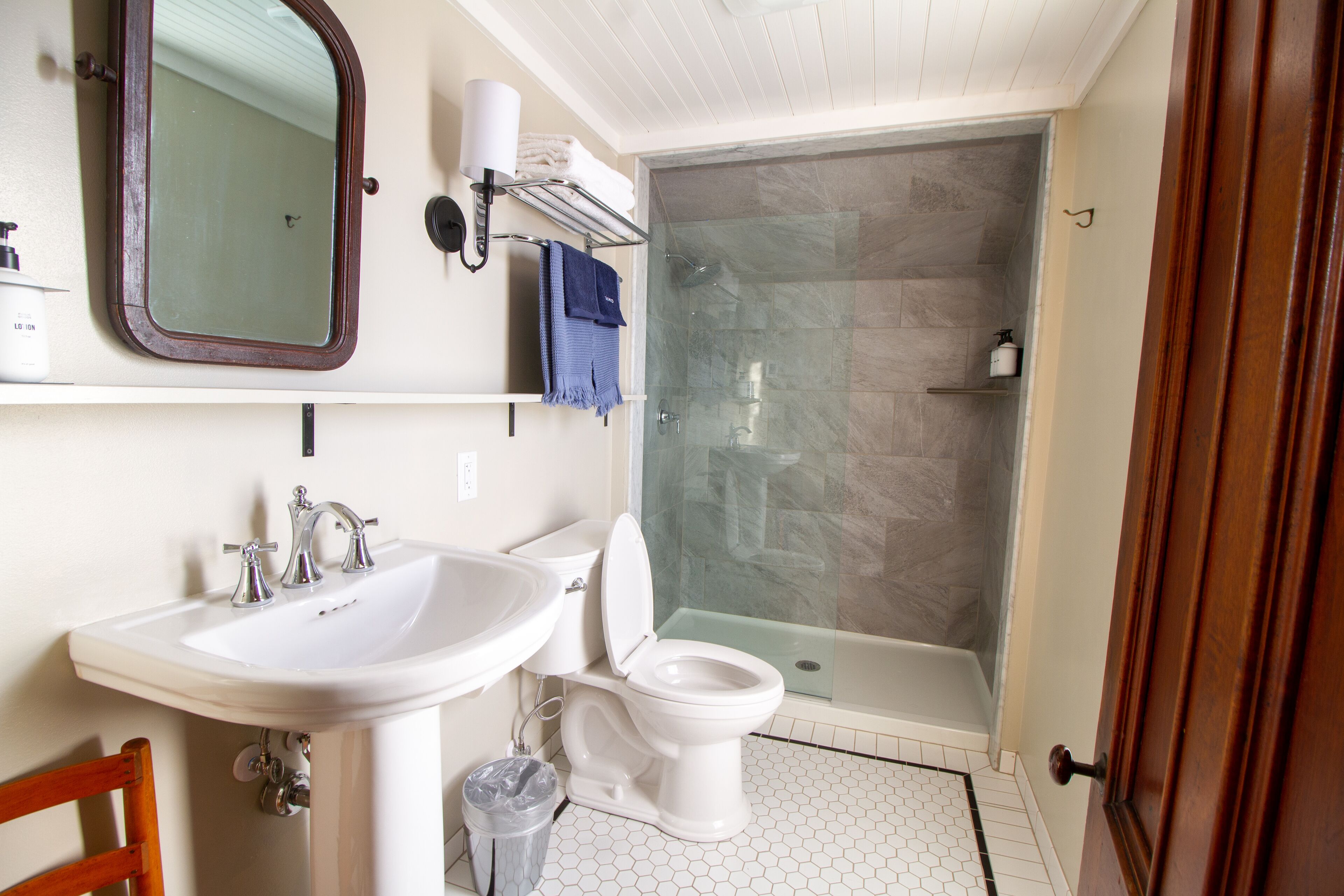 Ein Badezimmer mit Waschbecken, Toilette, Dusche mit Glastür und Spiegel.