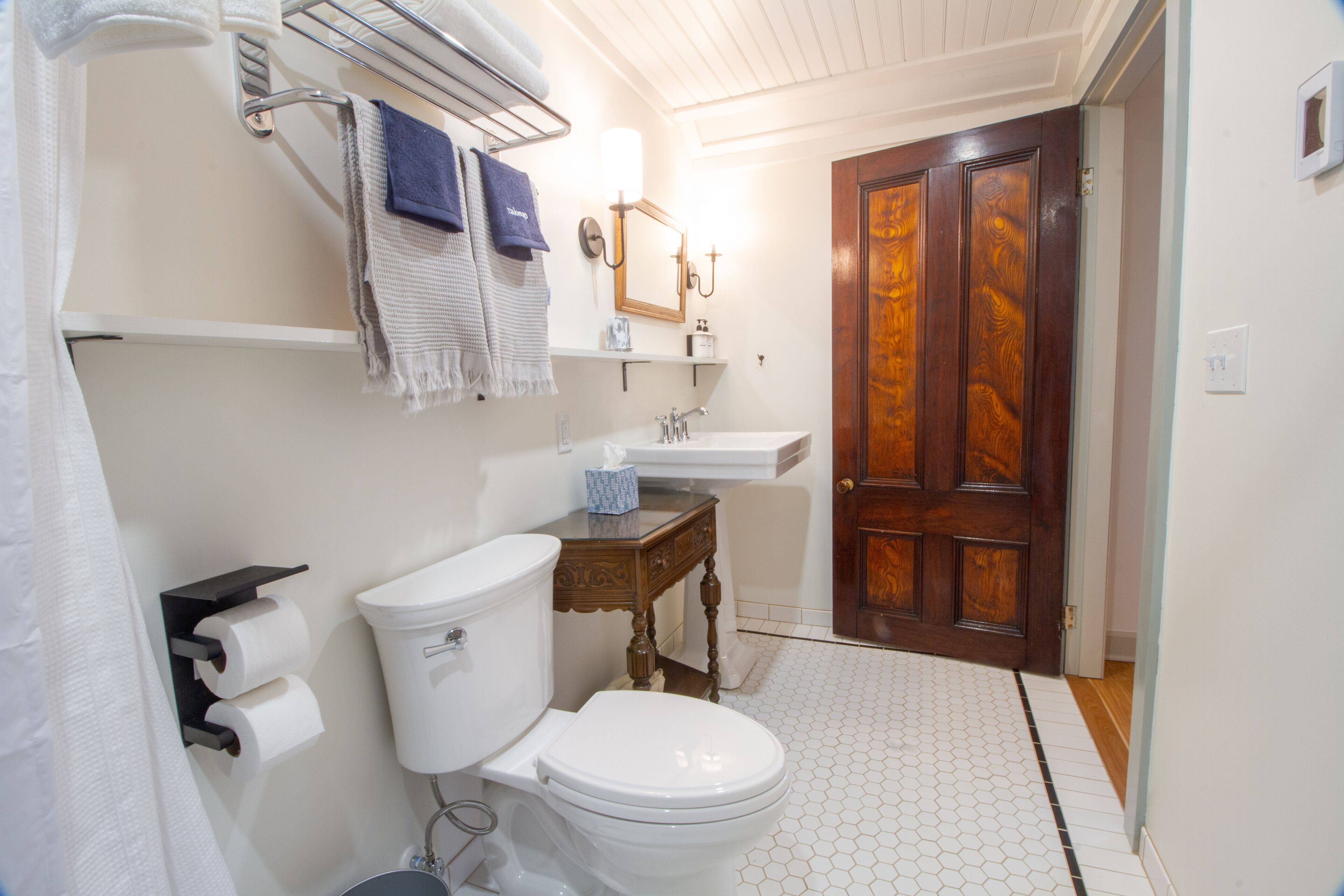 A bathroom with a toilet, sink, and wooden door.