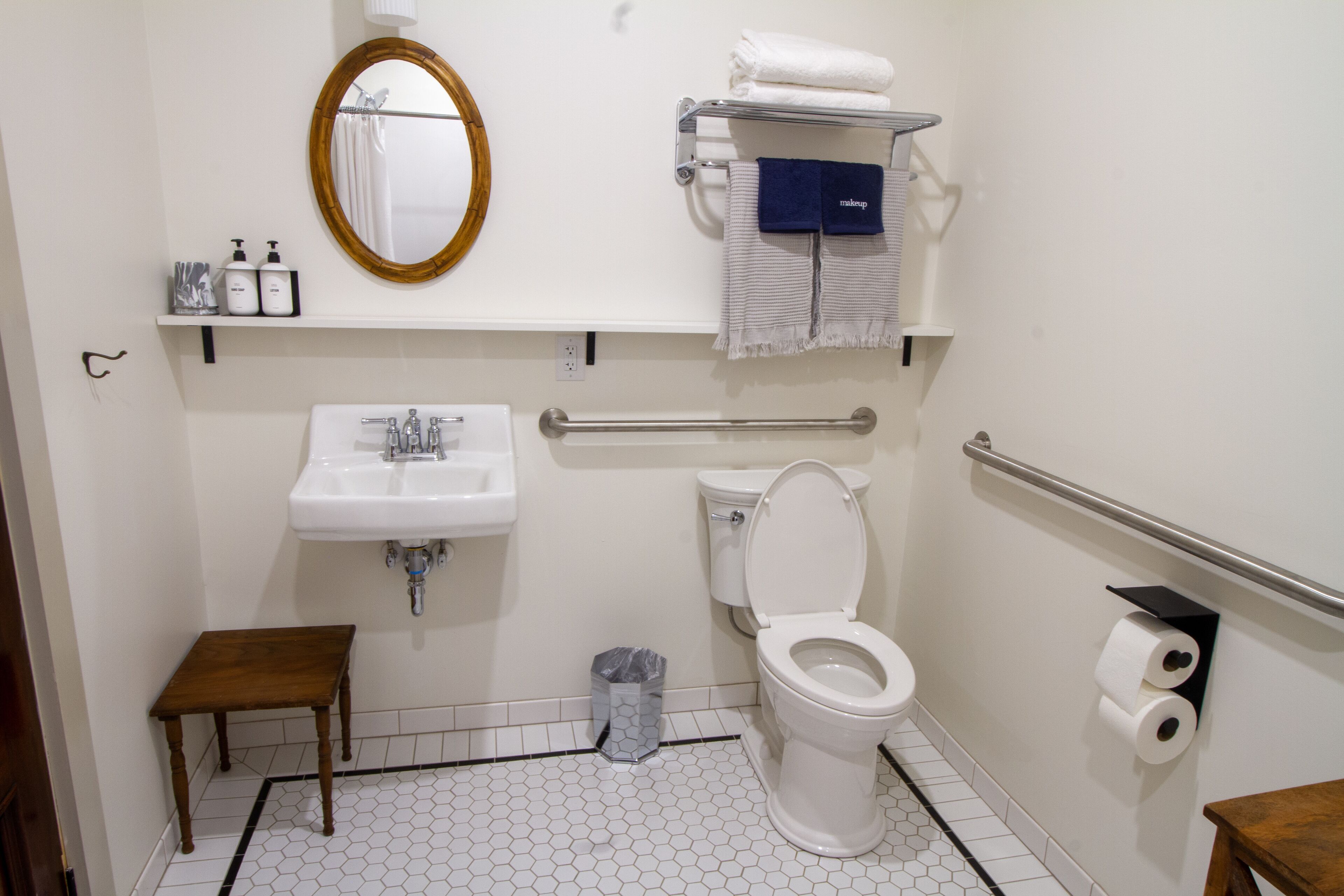 A bathroom with a white sink, toilet, and a wooden stool.