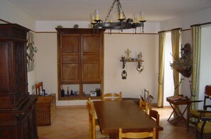 Un comedor con mesa y sillas de madera, una araña y un aparador.