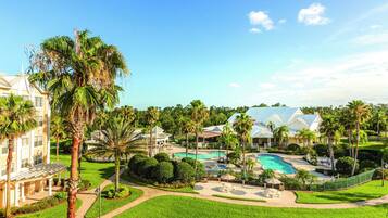 A resort with a swimming pool, palm trees, and a large building with a white facade.