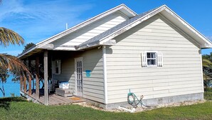 A single-story house with a porch, a small deck, and a view of the ocean.