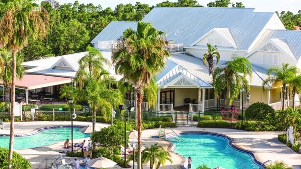 Ein Resort mit mehreren Schwimmbecken, Palmen und einem großen Gebäude mit blauem Dach.