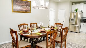 A dining room with a round table set for six, surrounded by wooden chairs with cushioned seats. - Clean & Cozy new Home, 30 mins to George Bush INTL/ downtown 5 mins to woodlands (Conroe)