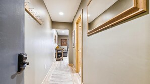 Ein Flur mit einer Holztür, einem Kleiderständer und einem gerahmten Bild an der Wand.