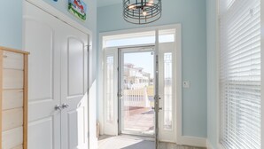 Un couloir doté d’un plancher en bois, de portes blanches et offrant une vue sur une maison à travers une porte vitrée.