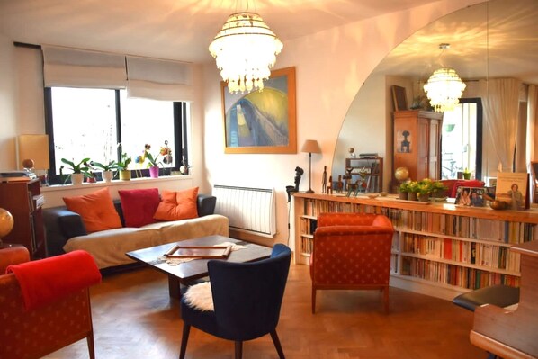 A cozy living room with a sofa, chairs, a coffee table, and a bookshelf filled with books.