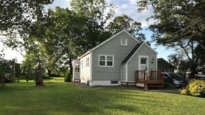 Une maison de plain-pied avec un porche à l’avant, une petite terrasse et une pelouse bien entretenue.