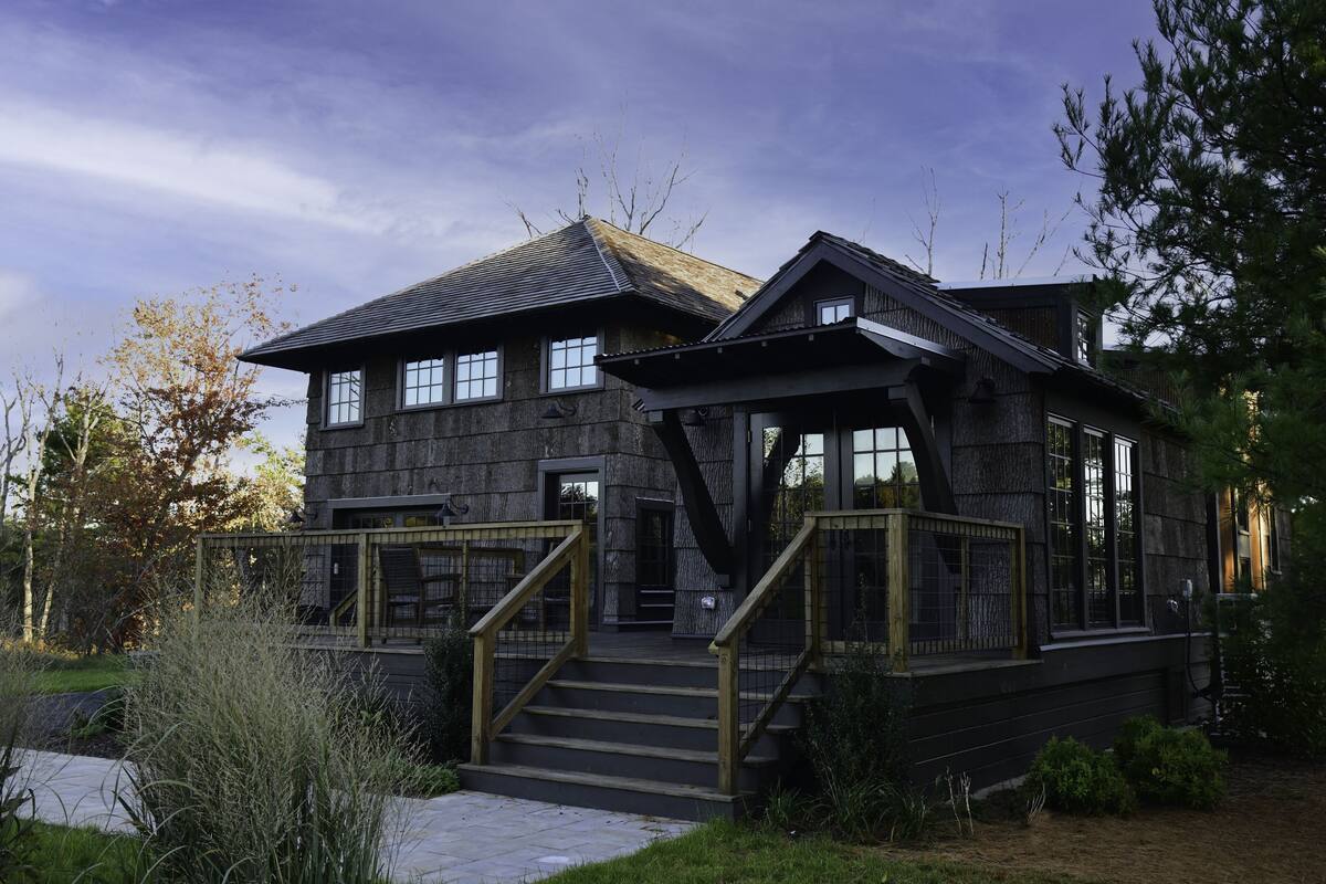 A two-story stone building with a wooden staircase and a covered porch.