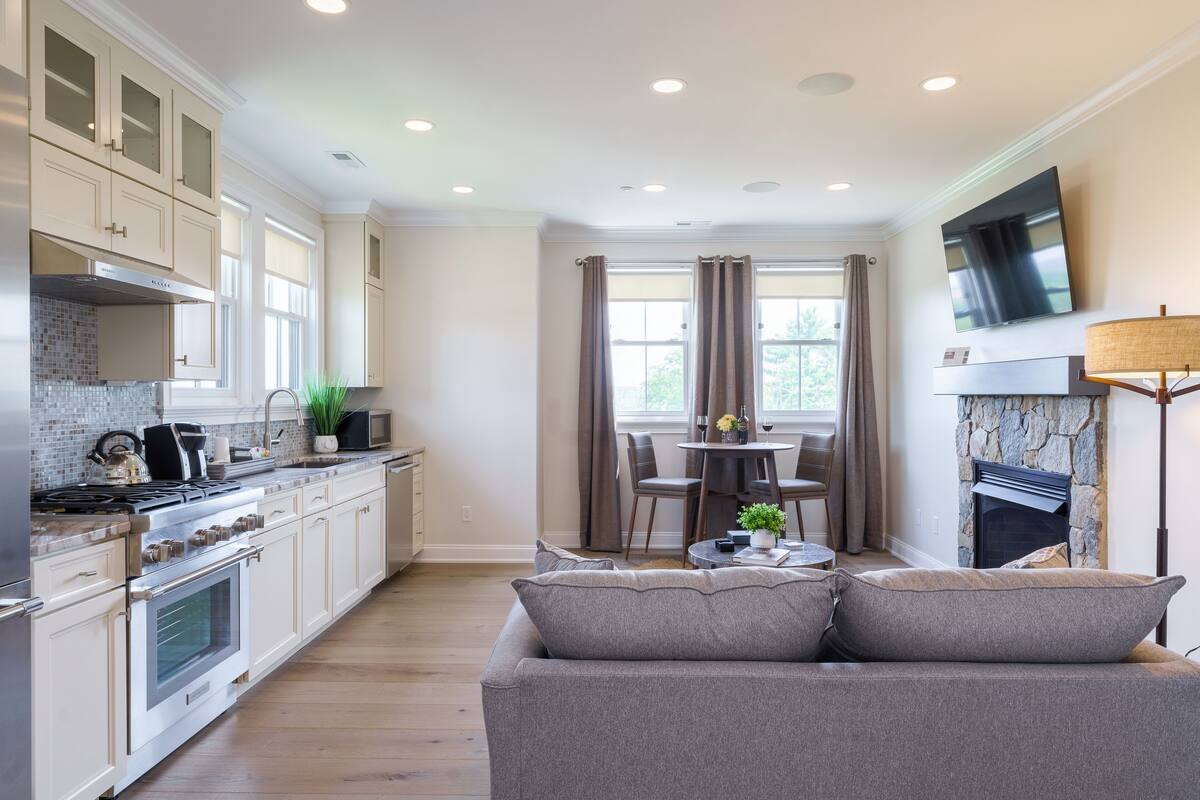 A modern kitchen with a dining area, a fireplace, and a TV mounted on the wall.