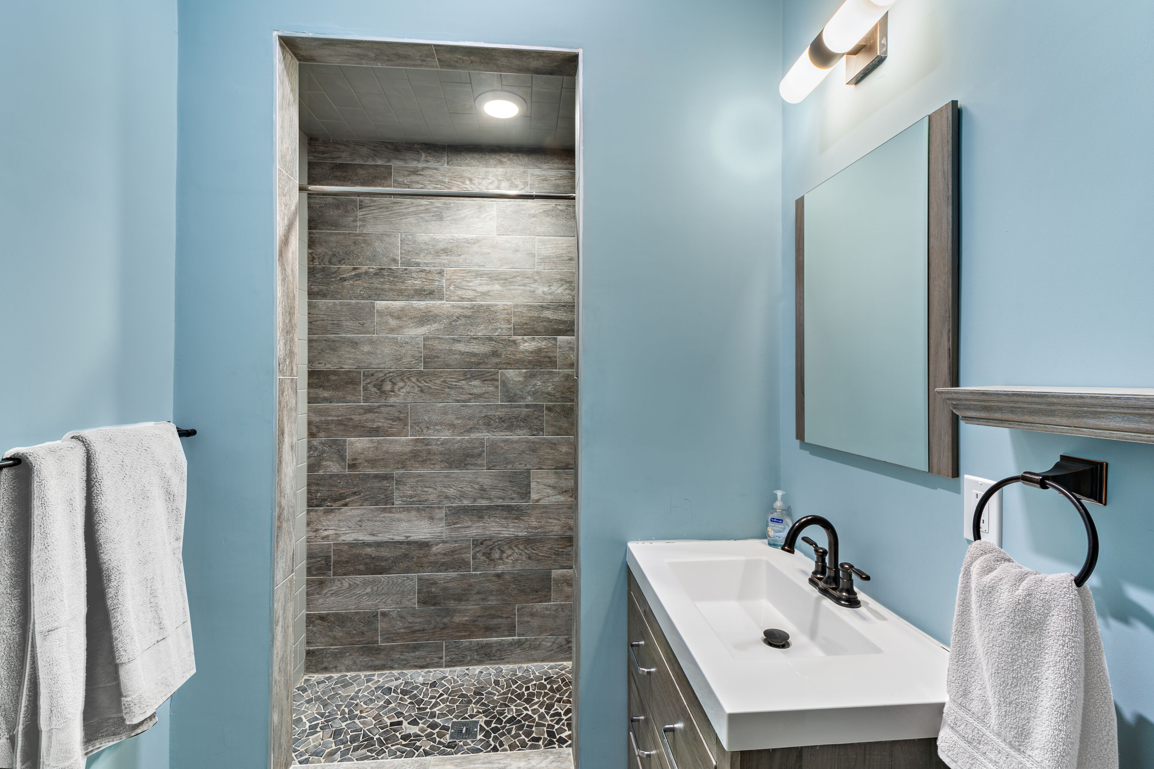 A bathroom with a shower, a sink, and a mirror.
