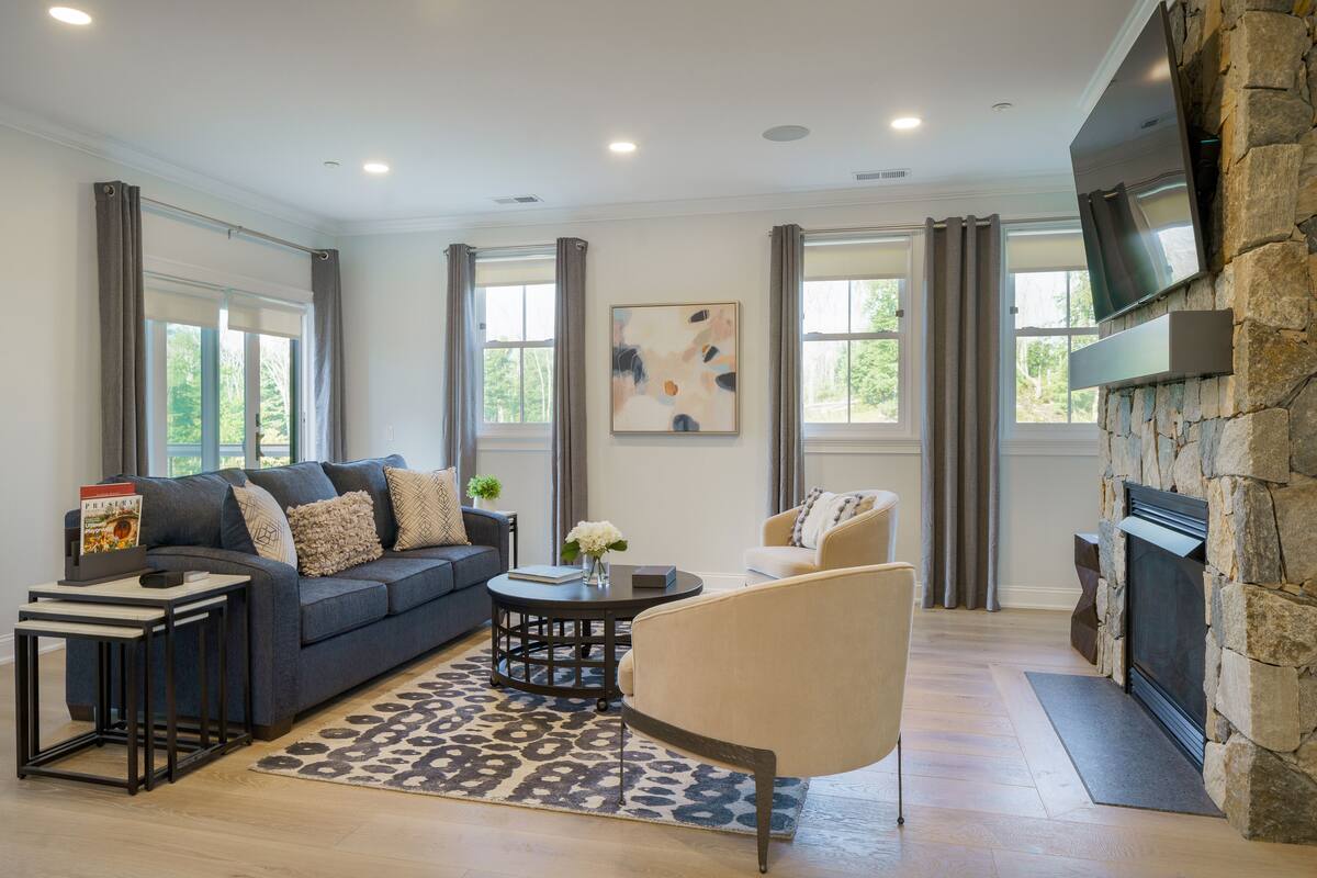 A living room with a sofa, armchair, coffee table, and fireplace.