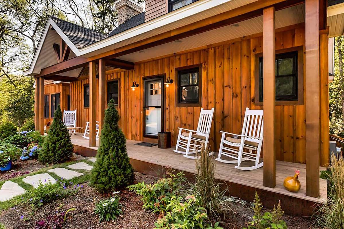 A wooden cabin with a porch, rocking chairs, and a small garden.