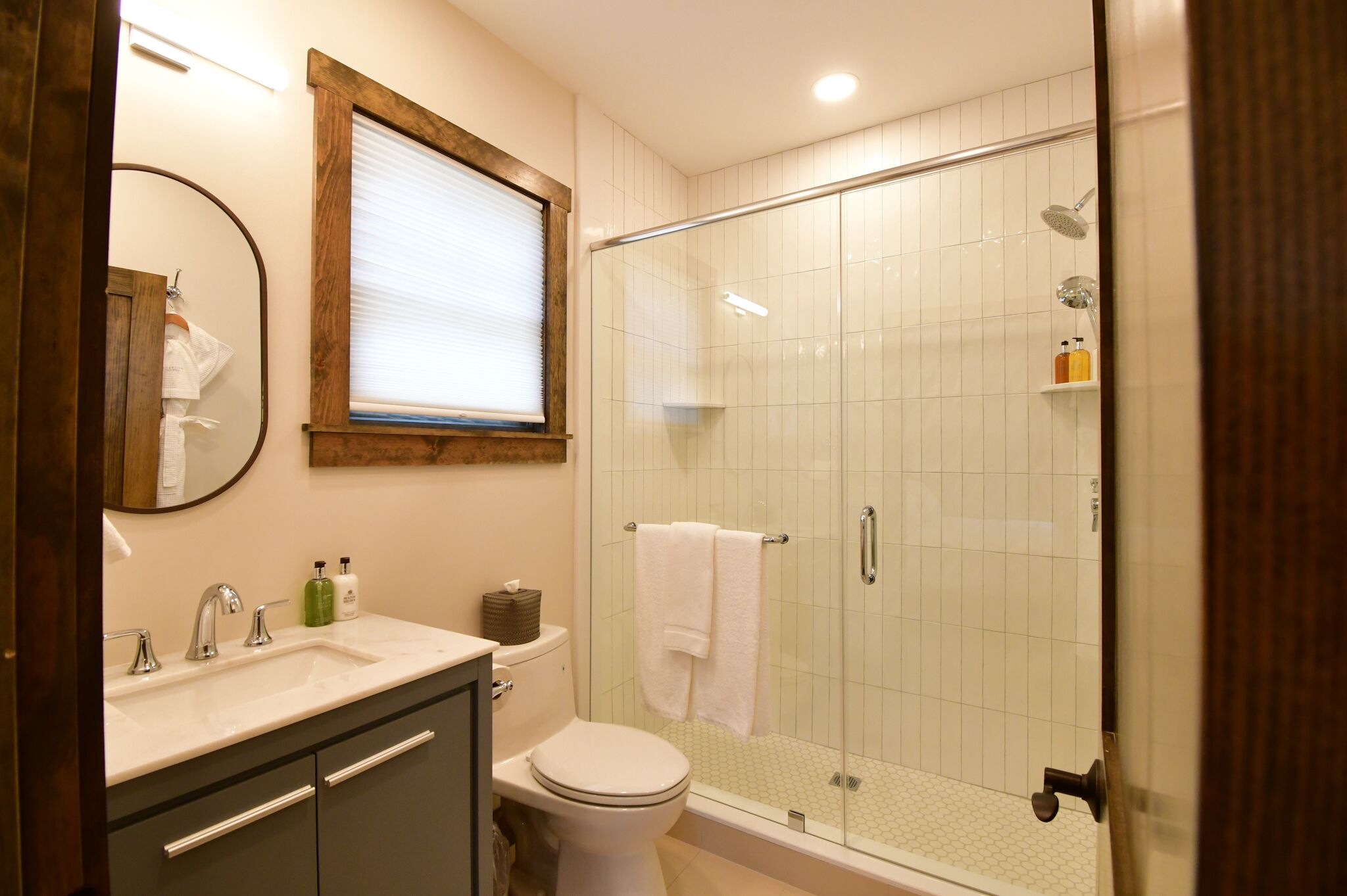 A bathroom with a glass-enclosed shower, a sink with a mirror, and a toilet.