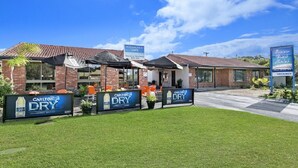 Un hotel con publicidad de Carlton Dry, una cafetería y un letrero de habitaciones disponibles.