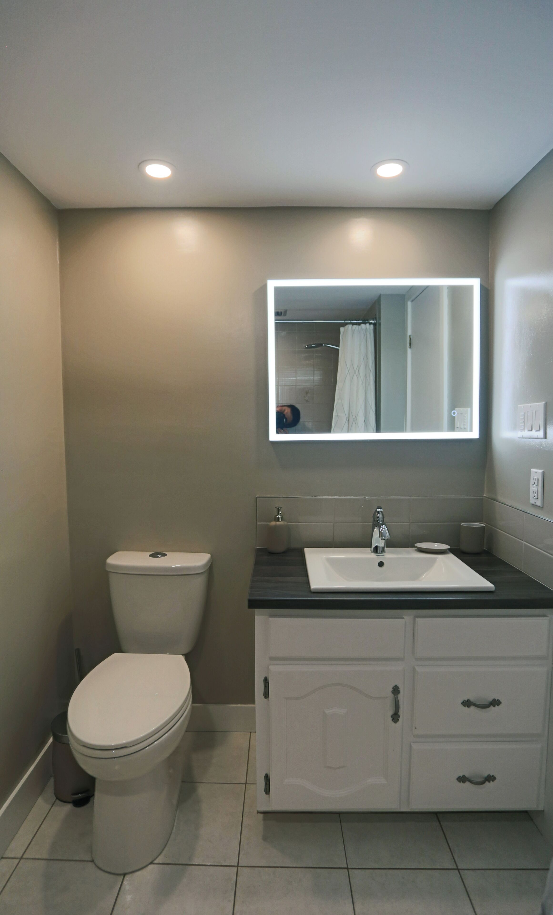 A modern bathroom with a toilet, sink, and vanity.