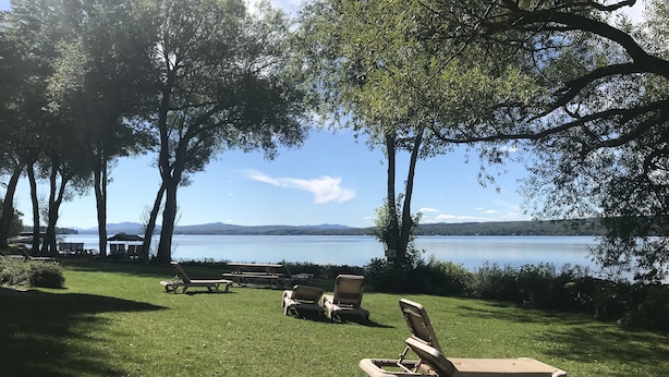 A grassy area with lounge chairs and picnic tables overlooking a lake.