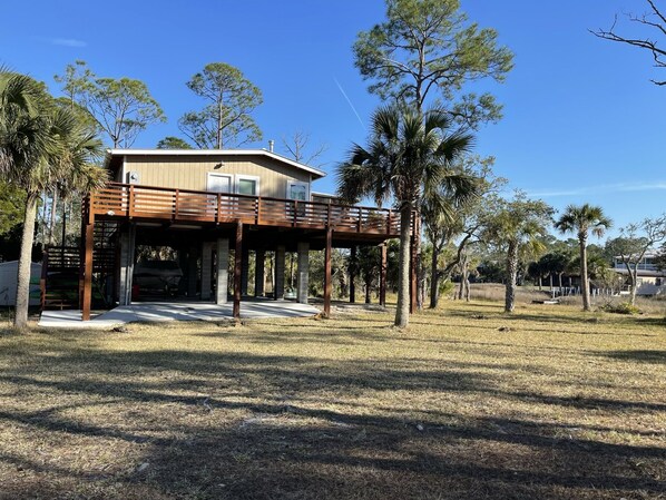 A two-story house with a wooden deck and a covered garage. - Rocky Creek Waterfront (Steinhatchee)