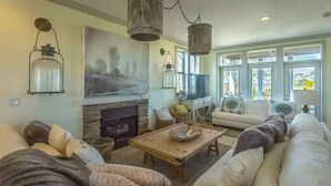 Ein gemütliches Wohnzimmer mit Kamin, bequemen Sitzmöglichkeiten und hängenden Laternen.