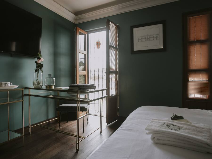 Una habitación con cama, escritorio, silla y ventana con persianas.