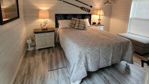 A cozy bedroom with a wooden ceiling, a bed with a quilted bedspread, two bedside lamps, and a small fan. - Crossroads to Pickwick Cabin SMOOTH SAILING (Iuka)