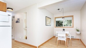 Ett modernt kök med vita skåp, en inbyggd ugn och en matplats med ett vitt bord och stolar.