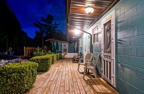 A wooden deck with chairs and a car parked nearby.