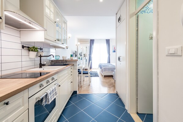 Una cocina moderna con armarios blancos, encimera de madera y suelo de azulejos azules.