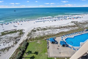 A beach resort with a swimming pool, beach umbrellas, and a clear view of the ocean. - Phoenix V 1016 | Splash Pad! | Beachfront | Private Balcony | Beach Getaways (Orange Beach)