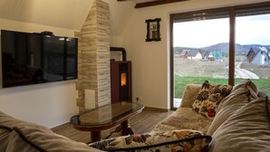 Una sala de estar acogedora con chimenea, un ventanal con vistas a casas y un televisor de pantalla plana montado en la pared.