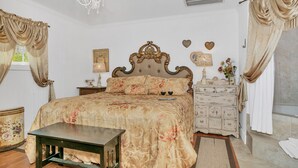 Ein klassisches Schlafzimmer mit einem großen Bett, einem Nachttisch, einer Kommode und einer Chandelier.