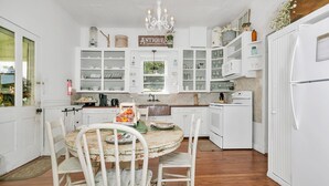 Una cocina con armarios blancos, una araña y una mesa de comedor con sillas.