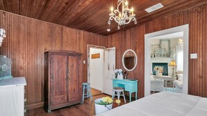 Una habitación con paneles de madera, una cama grande, un tocador con espejo y una araña.