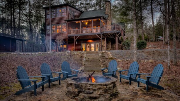 Une cabane avec un foyer en pierre et quatre chaises Adirondack.
