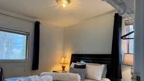 A hotel room with a bed, bedside lamps, a window with a view, and a ceiling light. - Walk Almost Anywhere at Alyeska Resort when you stay at Chair Four Por Favor! (Girdwood)