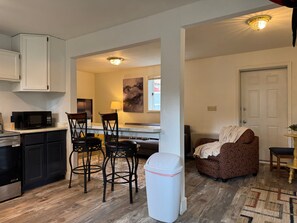 A compact kitchen with a microwave, cabinets, and a dining area with chairs and a table. - Walk Almost Anywhere at Alyeska Resort when you stay at Chair Four Por Favor! (Girdwood)