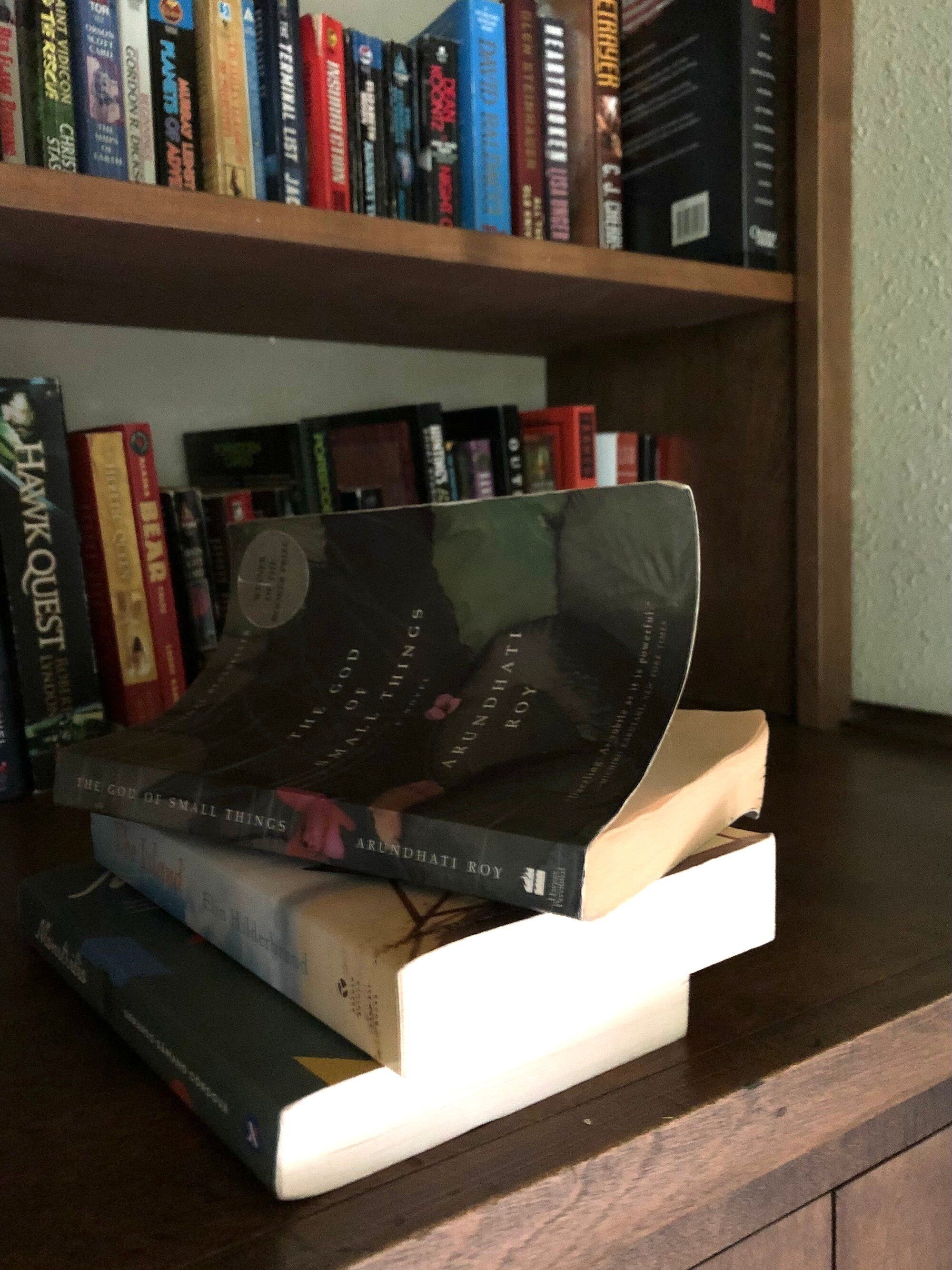 A stack of books on a wooden shelf.