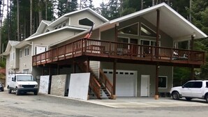 A two-story house with a covered porch and a garage. - Biker's Bungalow - Near Mendenhall Glacier and Auke Bay Offering DISCOUNT ON TOURS! (Juneau)