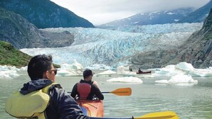 A kayaker paddling near a glacier with icebergs, surrounded by mountains. - Biker's Bungalow - Near Mendenhall Glacier and Auke Bay Offering DISCOUNT ON TOURS! (Juneau)